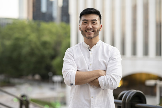 年轻的亚洲商人，双臂交叉的背景建筑图片下载