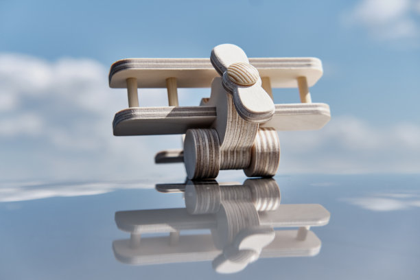 木制玩具轻型飞机双翼飞机在光滑的表面上多云的天空背景。图片下载