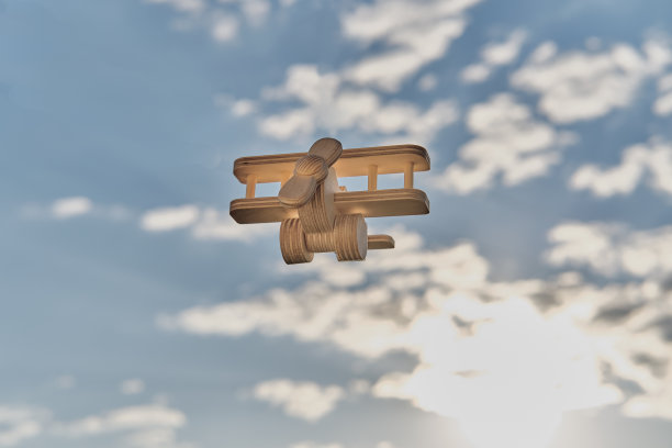 木制玩具、轻型飞机、双翼飞机在多云的天空中被阳光照亮。卡通航空。图片下载