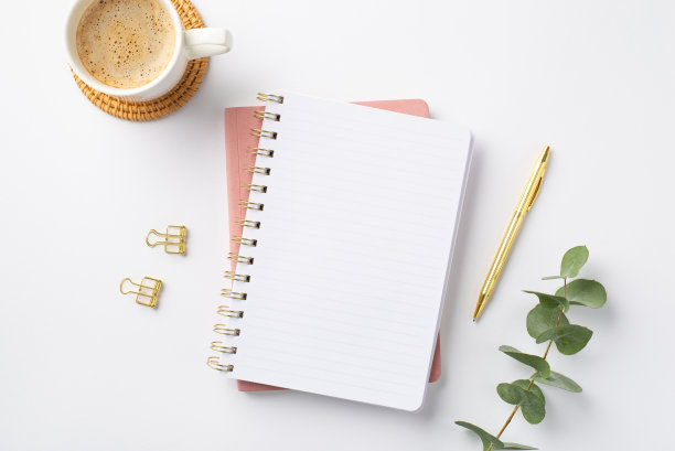 经营理念。俯视图的工作空间的照片打开记事本，金笔，活页夹，桉树枝和杯咖啡在藤垫上孤立的白色背景与空白的空间图片下载
