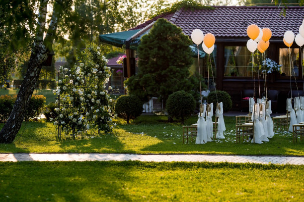 美丽的婚礼装饰。举行婚礼仪式的地方花的拱门，用织物装饰的金色椅子，球。时尚的装饰。插花是节日装饰的一部分。图片下载