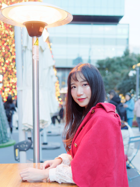 美丽的中国女孩肖像，黑色长发，红色圣诞服装坐在户外咖啡馆，微笑着对你，户外时尚肖像魅力年轻的中国开朗的时髦女人。图片下载