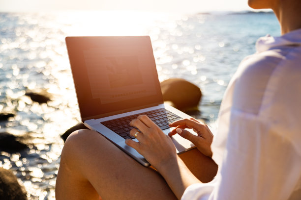在海滩上用笔记本电脑工作的陌生女性自由职业者图片下载