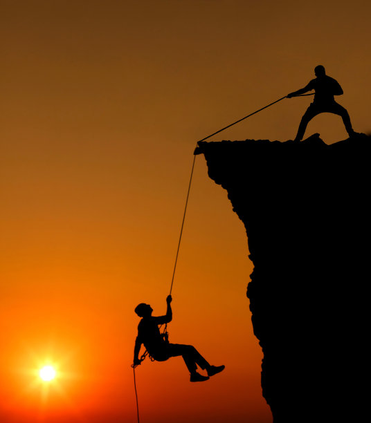 男人们帮助他的驴友爬山图片下载