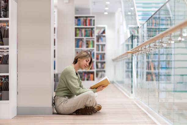 有书的沉思的中年妇女在图书馆度过空闲时间，享受阅读图片下载