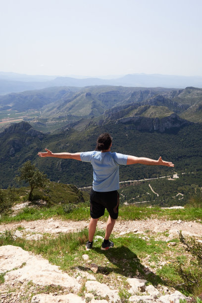 一个扎着马尾辫、双臂伸直的徒步旅行者从蒙多佛山顶眺望风景的垂直照片图片下载