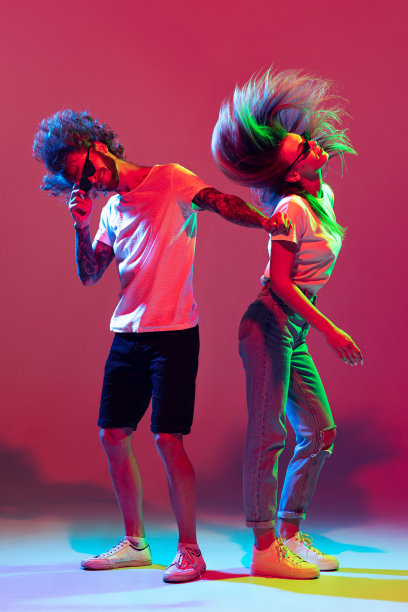 年轻时髦的男人和女人的肖像跳舞，在霓虹灯红色背景上孤立的姿势。夜总会的生活方式图片下载