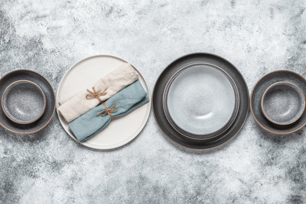 空盘子和亚麻餐巾排成一排。手工制作的工艺陶瓷。灰色的狼籍的背景。从以上观点。图片下载