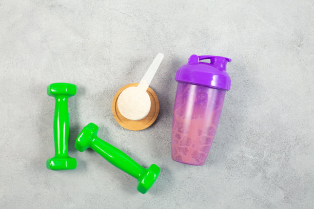 灰色混凝土背景上的震动器、哑铃和蛋白粉测量勺图片下载