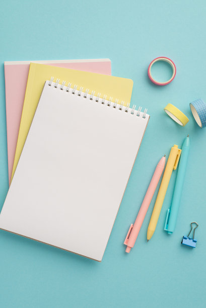 学习用品的概念。俯视图垂直照片的彩色文具堆叠笔记本笔活页夹和胶带上孤立的粉彩蓝色背景空白图片下载