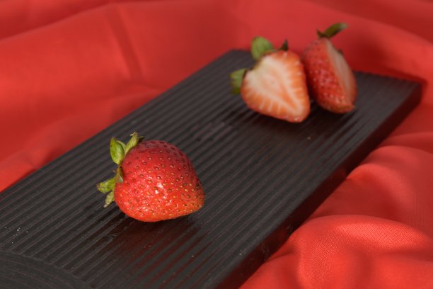 鲜艳的红色草莓在黑色的盘子与红色的背景图片下载