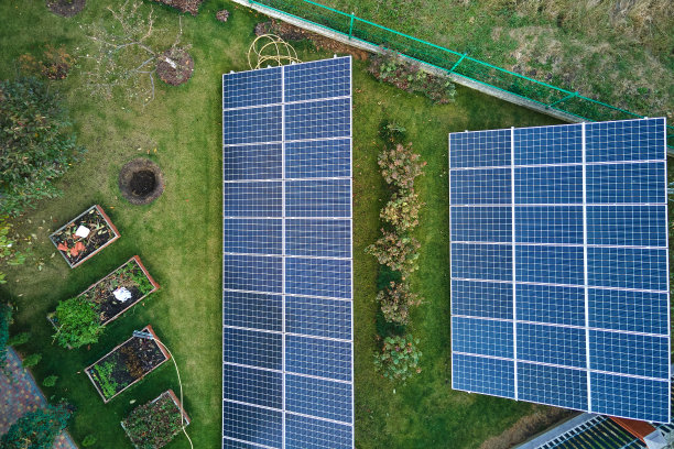 太阳能光伏板安装在后院地面的独立框架上，用于产生清洁的生态电能。自主住宅的概念图片下载