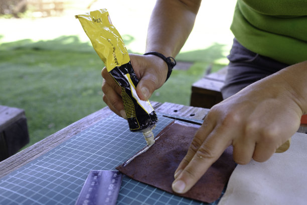在一个小手工场里，一个手艺人正在用她的双手制作一个皮包。图片下载