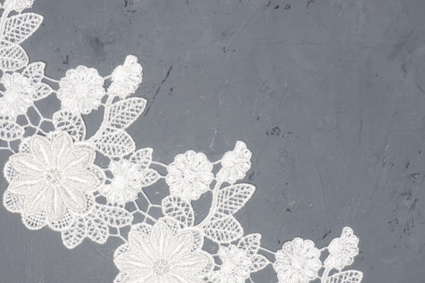 白色蕾丝花和叶子在黑色混凝土背景对角。温柔与粗糙的对比图片下载