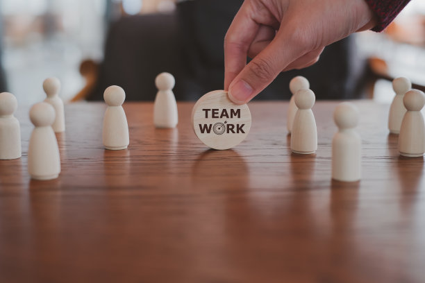 团队战略目标和目标。拿着木块的商人，用飞镖和不同的木雕人物进行团队合作。企业管理、战略、团队合作、领导力的概念。图片下载