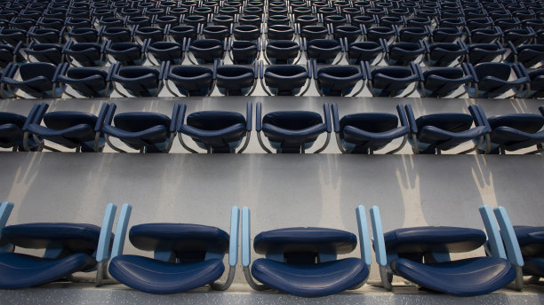 一张蓝色看台的照片，一个特别模糊的图片为背景，一个美丽的太阳耀眼的座位，一个巨大的电影院的椅子，很多空的座位，无人图片下载