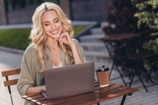 迷人的专注开朗的女孩肖像使用笔记本电脑写电子邮件在复杂的户外天气好图片下载