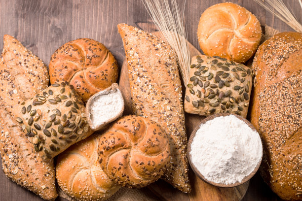 木桌上放着各种各样带种子的烤面包。面包店。食品安全的概念。图片下载