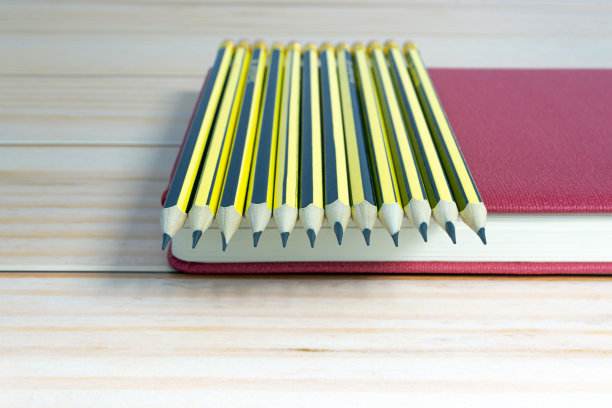 木制2b铅笔躺在木制桌子上的红色笔记本上。副本的空间。图片下载