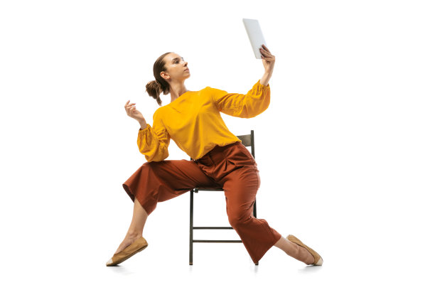 年轻漂亮的女孩的肖像，穿着时髦服装的办公室工作人员在扶手椅上跳舞孤立在白色的工作室背景。美概念、商业、芭蕾、艺术、舞蹈风格图片下载