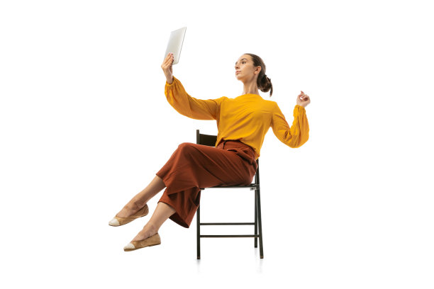 年轻漂亮的女孩的肖像，穿着时髦服装的办公室工作人员在扶手椅上跳舞孤立在白色的工作室背景。美概念、商业、芭蕾、艺术、舞蹈风格图片下载