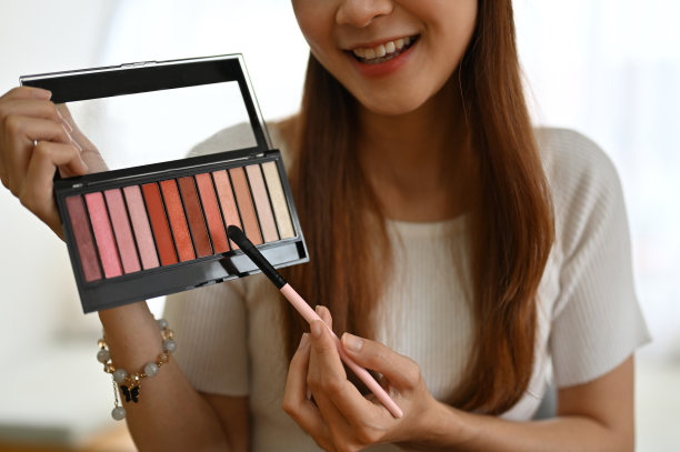 亚洲女性美妆博主展示了一个眼影调色板，制作了一个化妆视频。图片下载