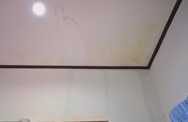 天花板上黄色的雨渍墙上的污渍。灯泡。短路的风险。水迹从天花板边缘一直流到墙上。图片下载