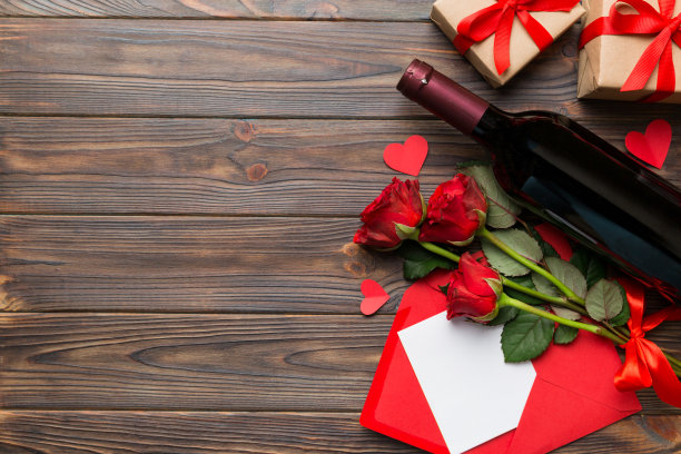 情人节作文用红酒、玫瑰花和礼盒放在桌上。俯视图，平铺。节日的概念图片下载