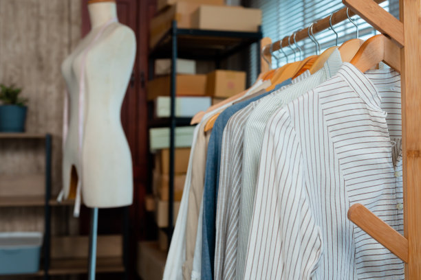 一家在线服装店的栏杆上挂着衬衫，背景是人体模型，还有几十个排队等待投递的包裹盒。图片下载