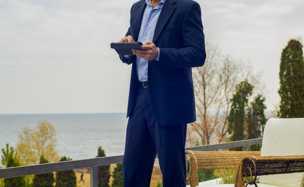 一名男子在露台上使用平板电脑。投资者律师首席总裁专业人士在家里的露台上使用平板电脑。商业咨询视频银行。图片下载