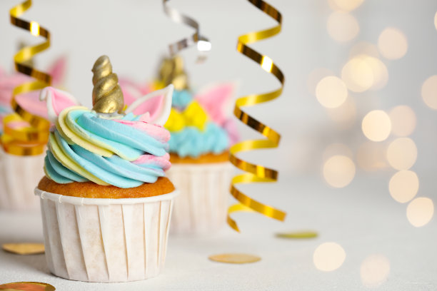 可爱甜美的独角兽纸杯蛋糕在白色的桌子上，文字和散景的空间。节日的治疗图片下载