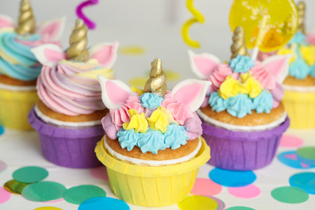 可爱甜美的独角兽纸杯蛋糕和白色桌子上的节日装饰图片下载
