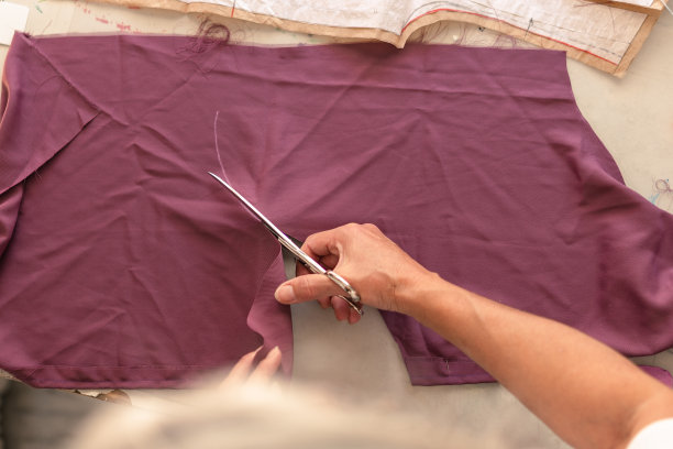 女人沿着粉笔画的线裁剪布料图片下载