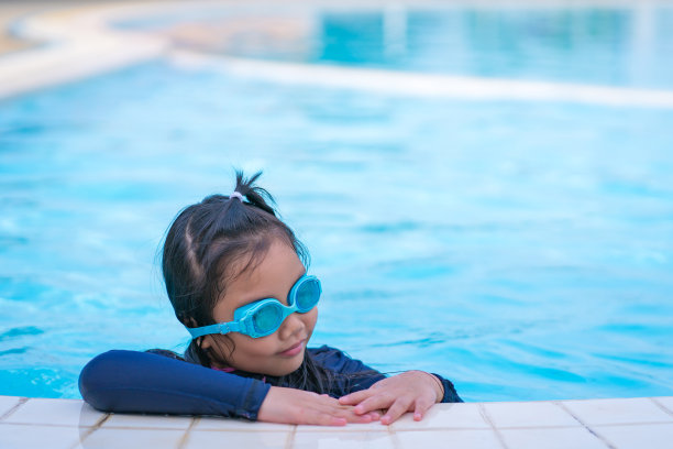 可爱的小女孩戴着墨镜在游泳池里微笑图片下载