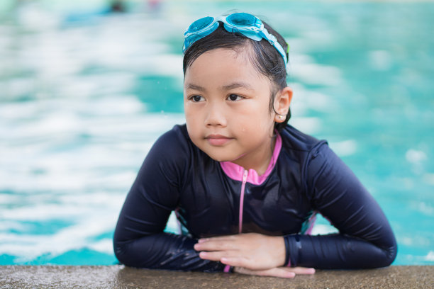 可爱的小女孩戴着墨镜在游泳池里微笑图片下载