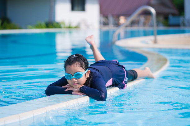 可爱的小女孩戴着墨镜在游泳池里微笑图片下载