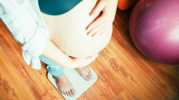 孕妇体重增加。幸福的孕妇站在体重秤上。概念产妇，怀孕，分娩。图片下载