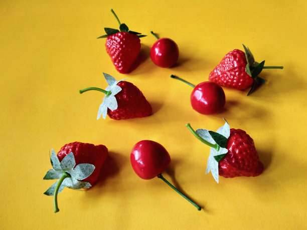 假草莓和樱桃被隔离在橙色背景上图片下载