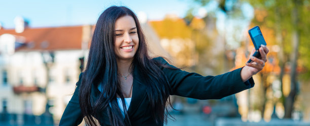 年轻微笑漂亮漂亮的女商人自拍在街上夏天的晚上。横幅，广告。图片下载