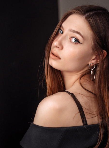 漂亮女人的肖像深色头发，蓝眼睛，在黑色上摆姿势图片下载