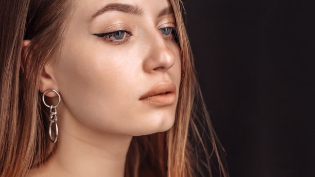 一个严肃美丽的年轻女人的特写脸在黑色的背景上图片下载