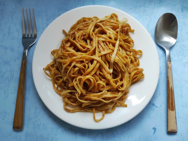 中式炒面放在白色的盘子里，配上餐具图片下载