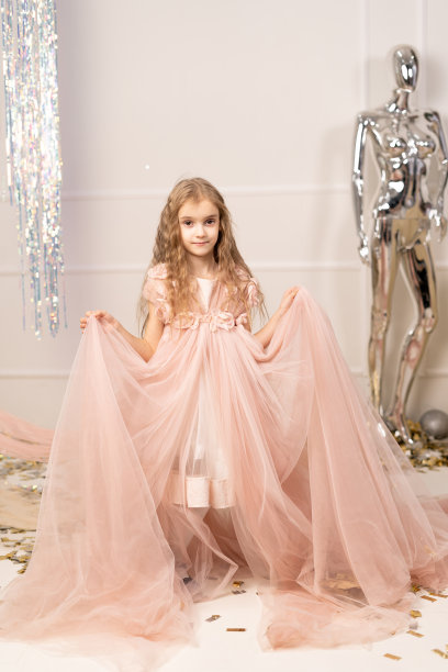 欢快的小女孩，金色长发，薄纱公主裙，粉红色的工作室背景。明亮的嘉年华庆祝活动，生日派对，可爱的孩子玩得开心图片下载