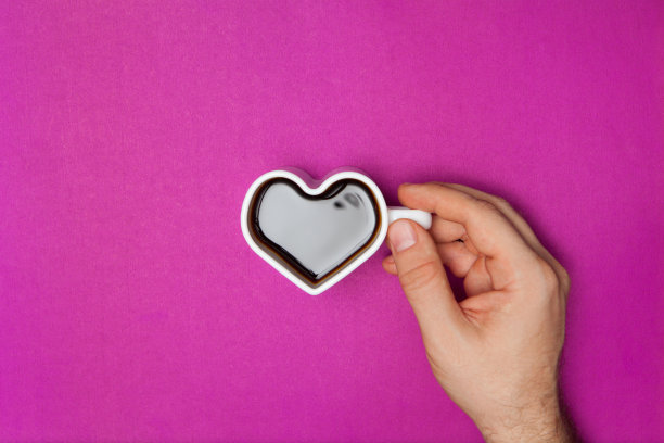 男人的手握着心形的咖啡杯。图片下载