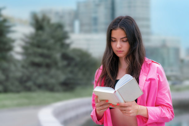 漂亮的年轻黑发女人手里拿着书读小说。图片下载