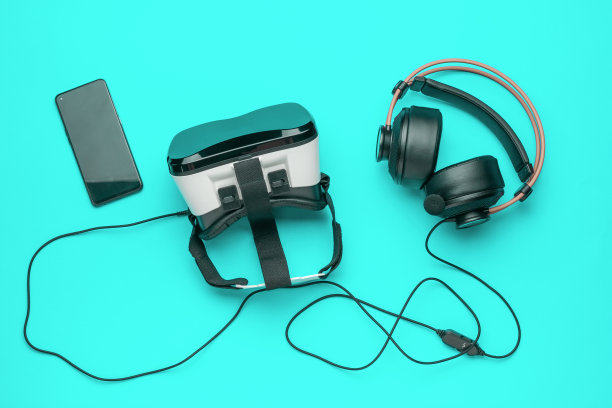 灯光背景下的VR眼镜、智能手机和耳机。一个流行的虚拟现实小工具。图片下载