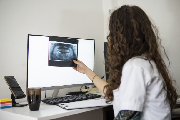 白人护士在医生的办公室里看着牙齿的整形图像。图片下载