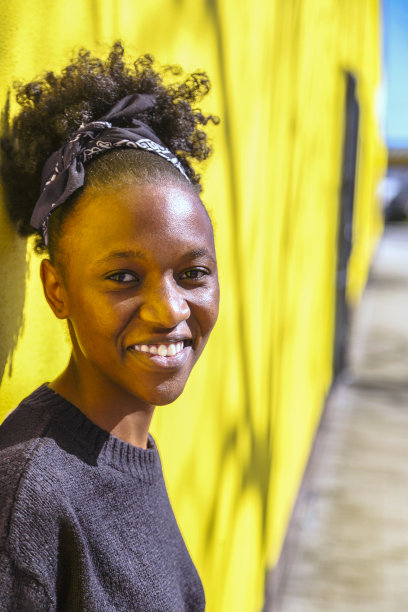 年轻的非洲妇女与发髻在黄色的背景图片下载