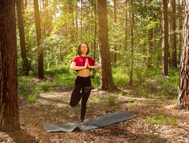年轻的女性在公园的树旁闭眼冥想，站在树的位置，做瑜伽图片下载
