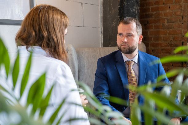 年轻的女士在商务服装和英俊的中年成功男性在咖啡馆的桌子谈话的背影图片下载